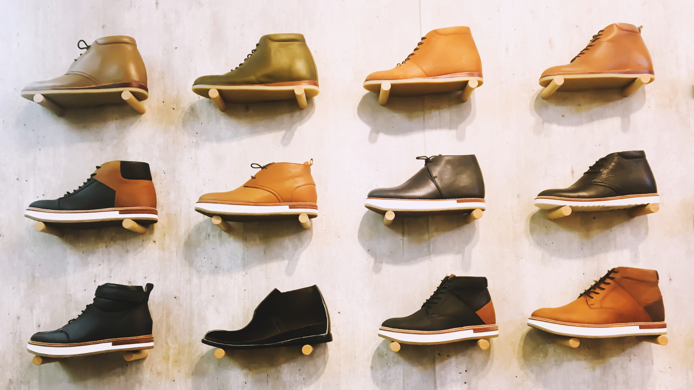 An organized retail display of neutral-colored men's shoes lined up neatly on a wall rack