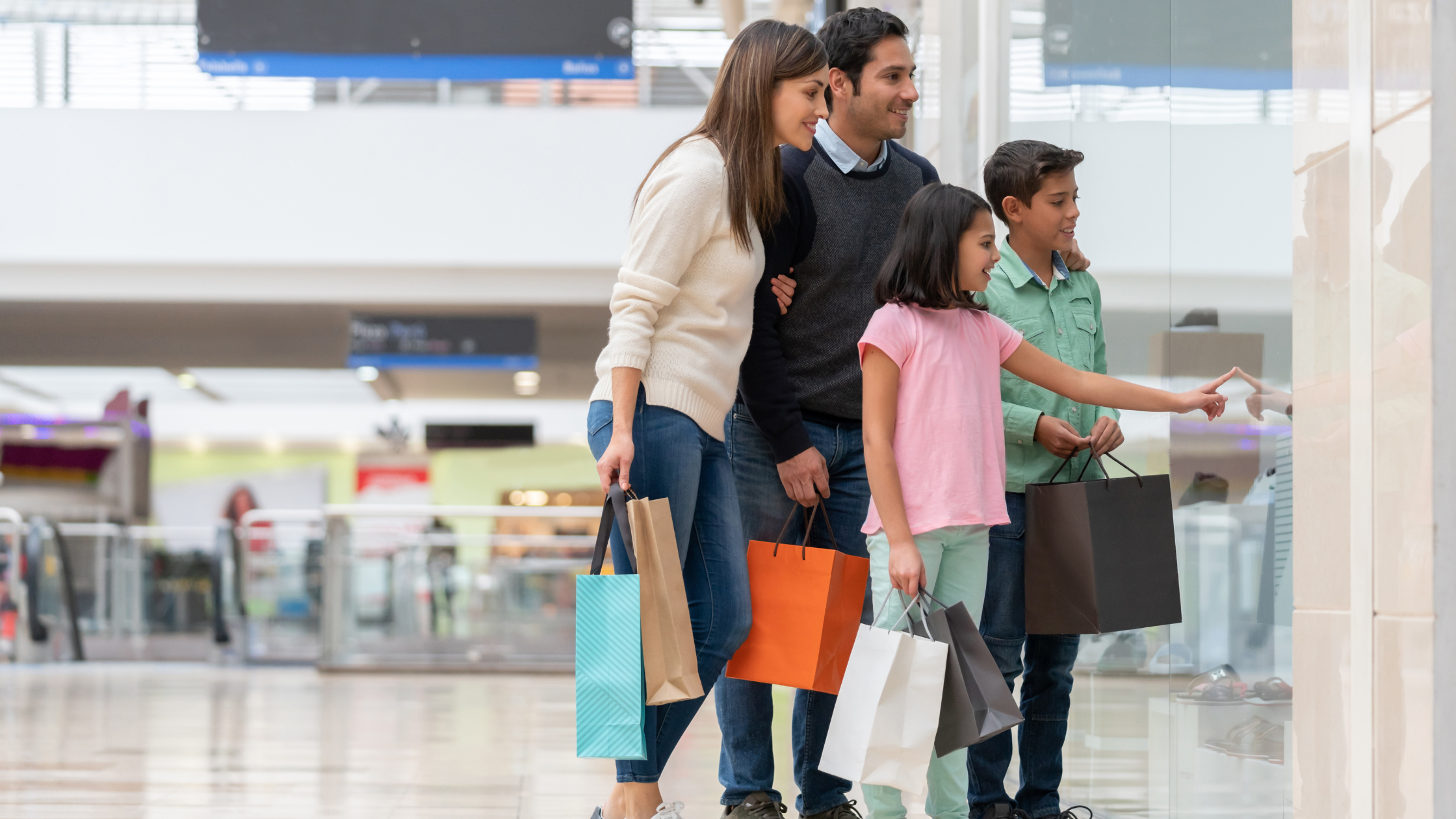 A family with a preteen son and daughter window shopping in a mall